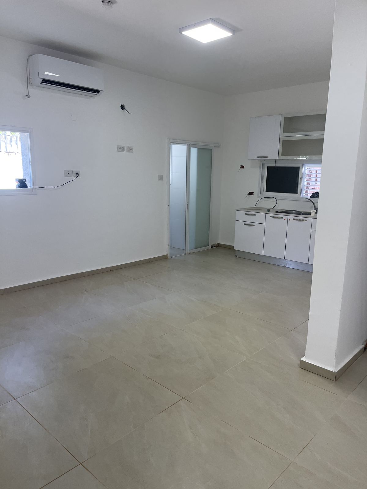 סלון ומטבח אחרי שיפוץ, קירות לבנים וריצוף אפור